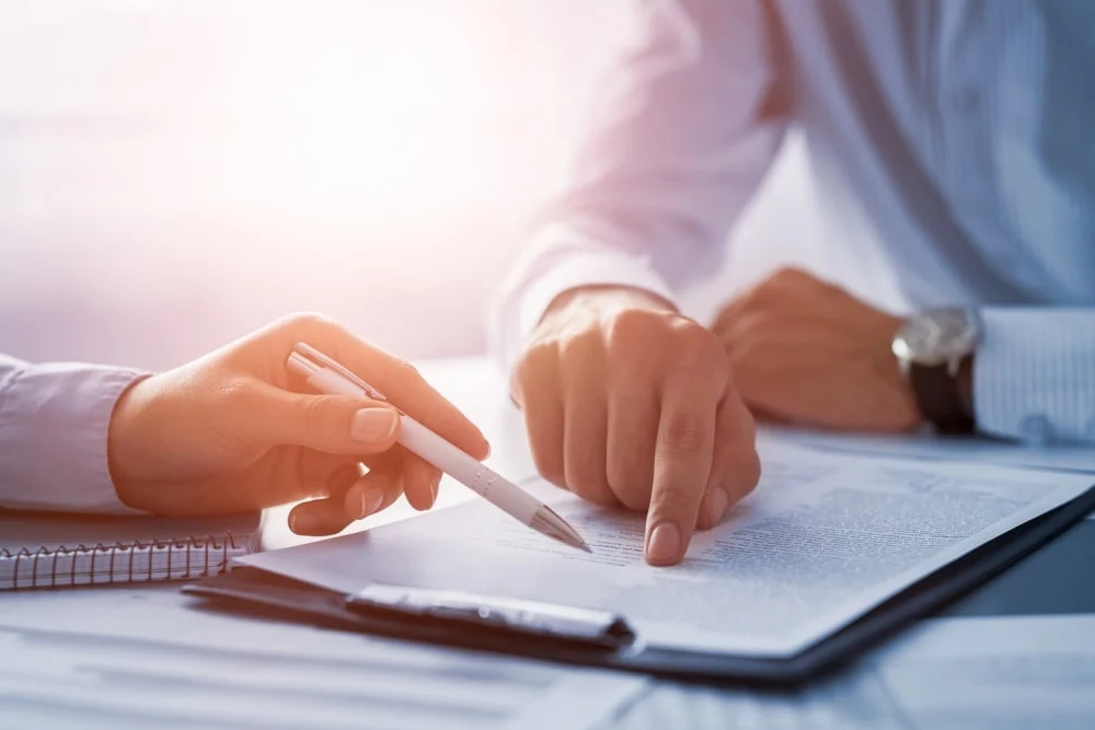 Person pointing to a line on a form they are filling out.